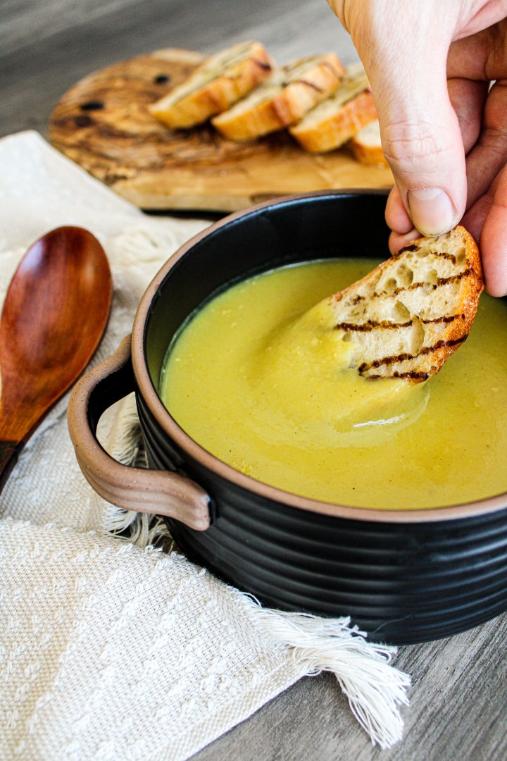 curried potato leek soup with bread being dipped into it